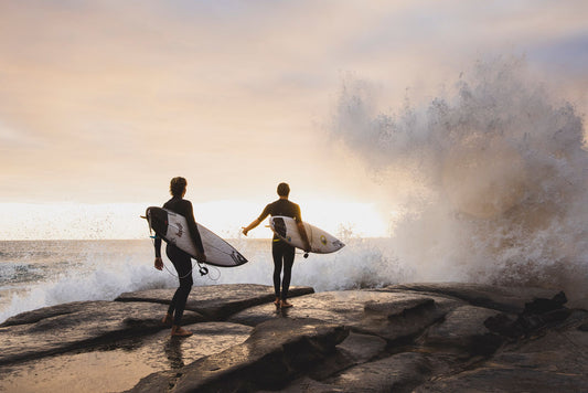 2 O'Neill sponsored surfers about to jump off a rock to go surfing in winter