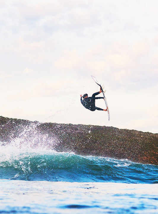 Jordi Smith doing a huge aerial off the back of a wave wearing his winter O'Neill wetsuit