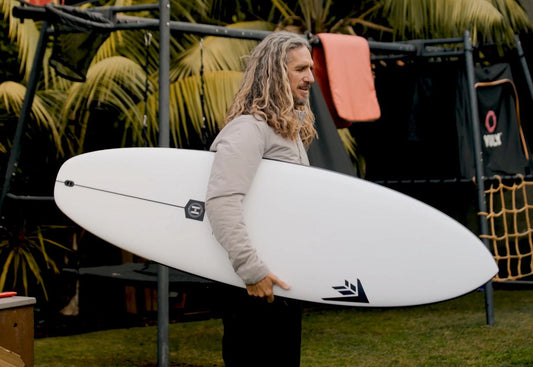 Rob Machado holding a new Machado Groove surfboard in helium construction