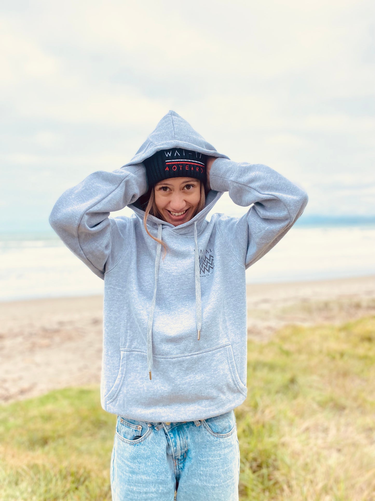 Wai-Tai Kaitiaki Maori Shark Hoodie in grey marle from front at Midway Beach Gisborne on model wearing beanie