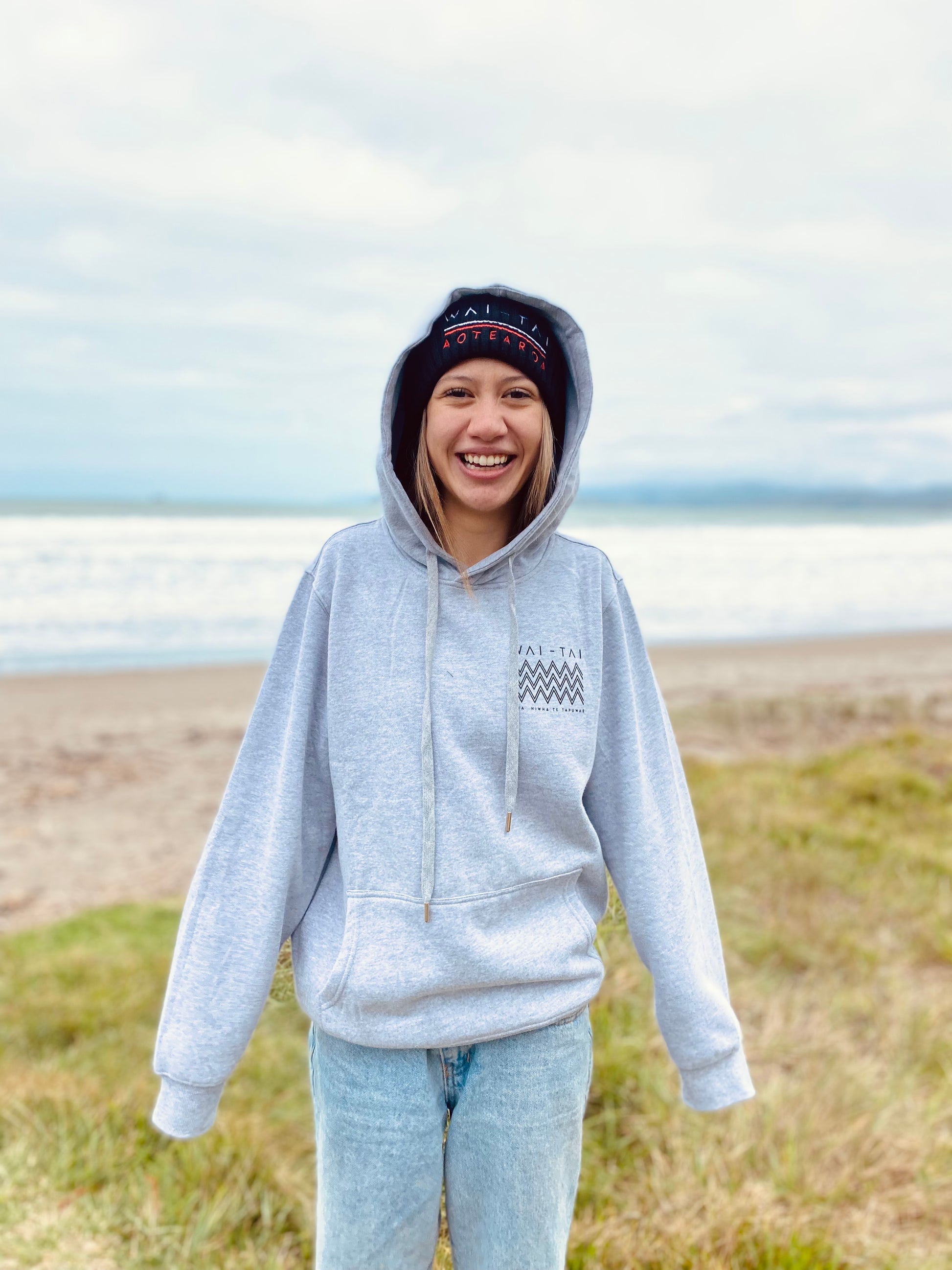 Wai-Tai Aotearoa Tohu Fisherman Beanie in black on model from front in grey kaitiaki hoodie