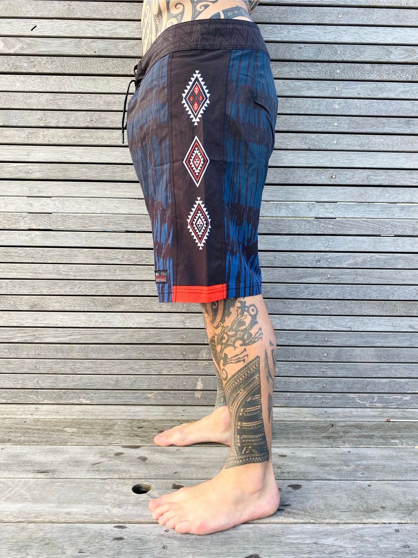 Wai-Tai Aotearoa Piu 4 Way Stretch Maori Boardshorts on Maia Gibbsform the side