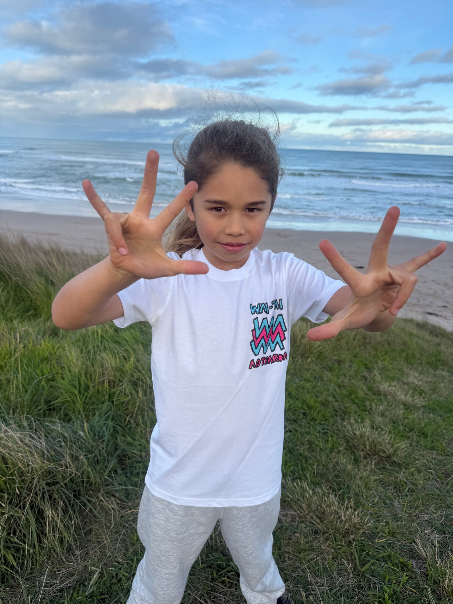 Wai-Tai Kids Mura Maori t-shirt in white from front view at Okltu beach in Gisborne