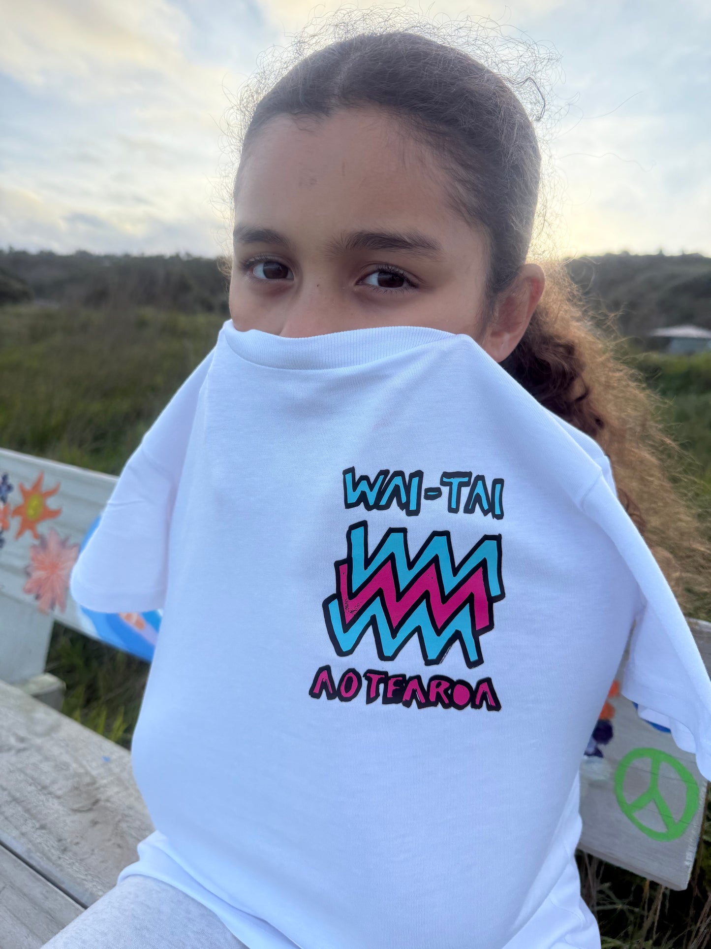 Wai-Tai Kids Mura Maori t-shirt in white from front view at Okltu beach in Gisborne close up
