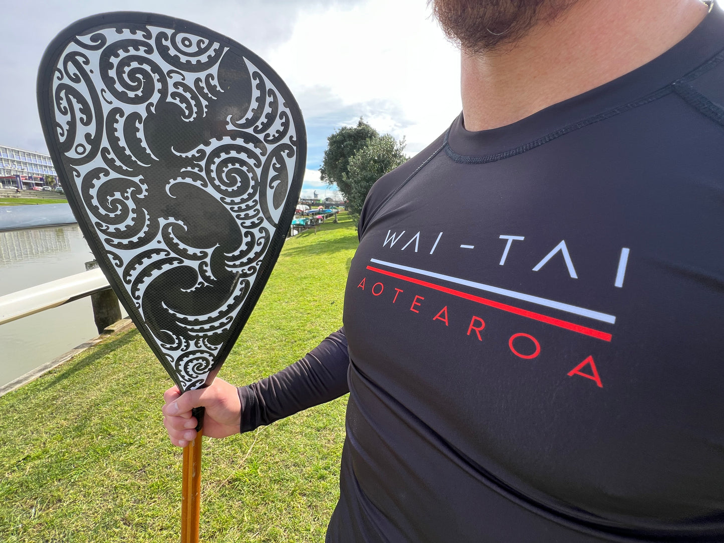 Wai-Tai Aotearoa Patiki Thermal Longsleeve Rash Top on Maia Gibbs holding a waka paddle close up front