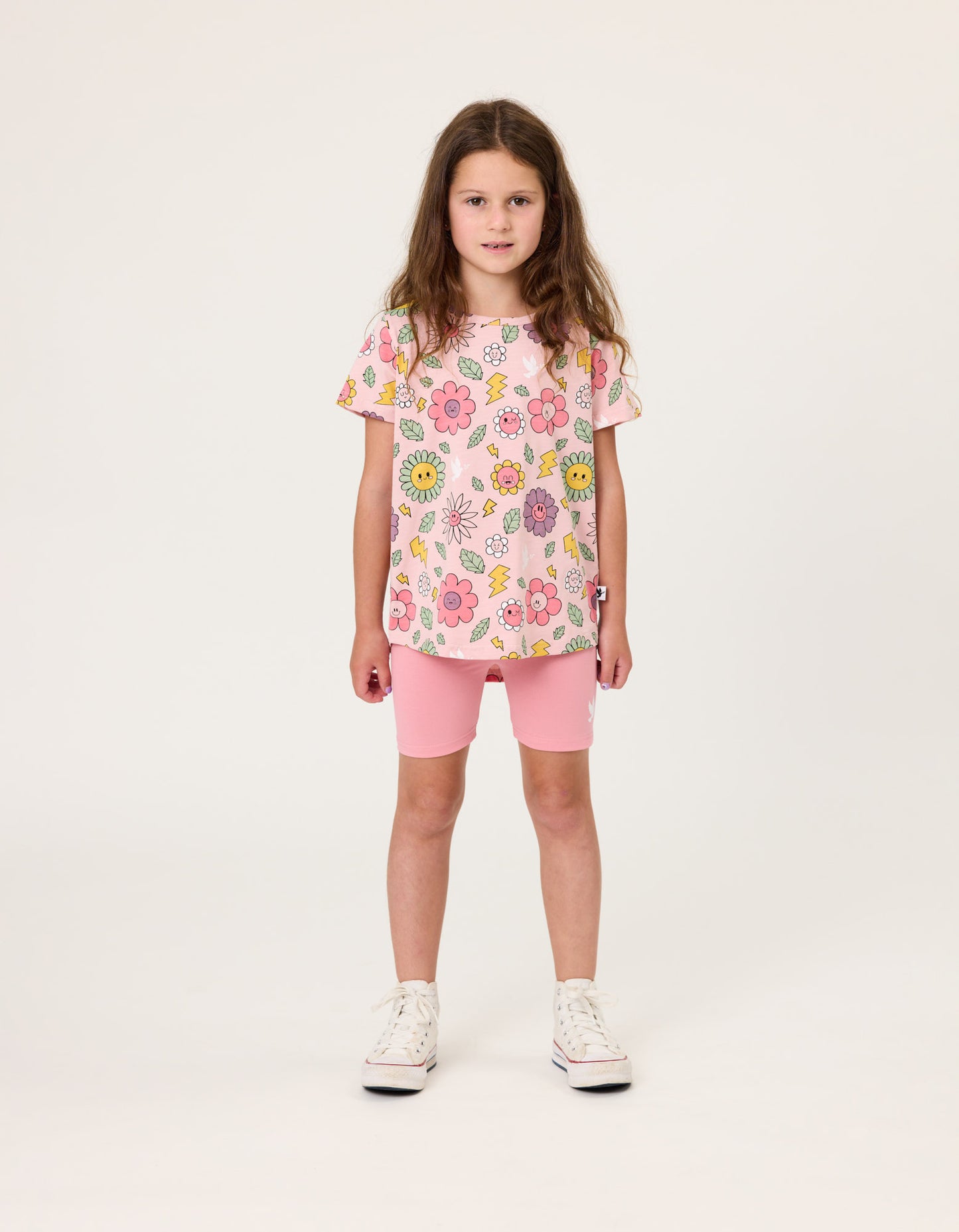 Kissed By Radicool Smiley Flowers Girls T-Shirt in pink on dark-haired model in pink bike shorts from front
