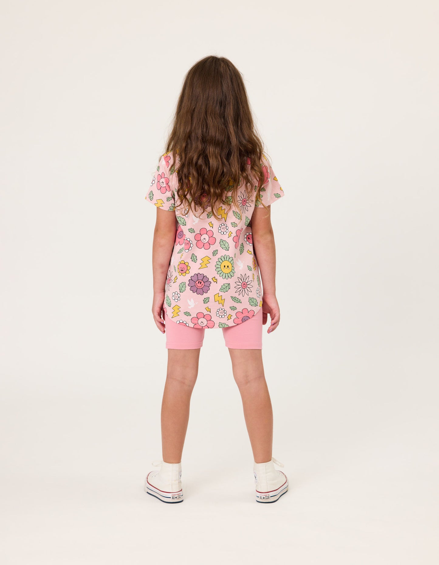 Kissed By Radicool Smiley Flowers Girls T-Shirt in pink on dark-haired model in pink bike shorts from rear