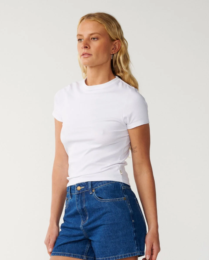 Rip Curl Tabby Women's Denim Shorts in mid blue on model in white tee from the front left side angle