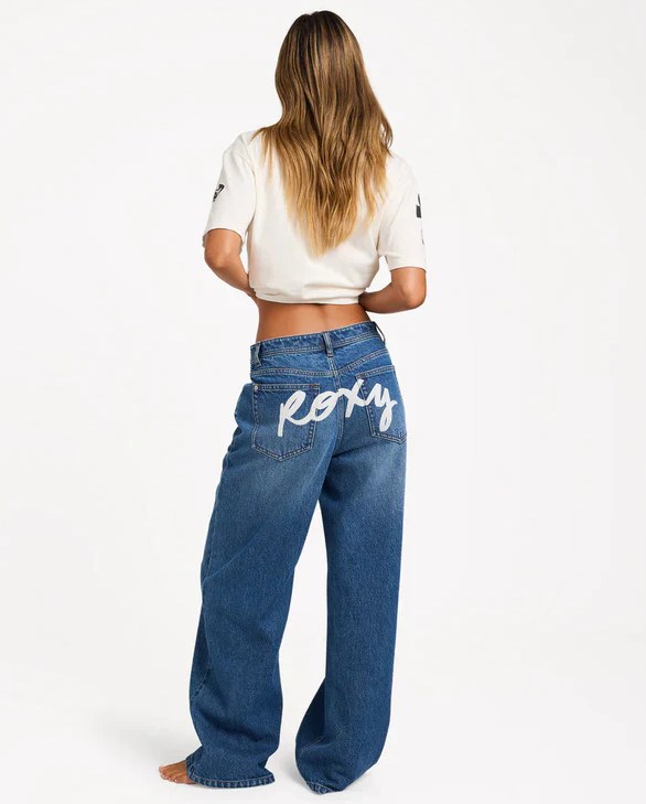 Roxy Backslider Denim Pant in blue on model in white Roxy tee from rear