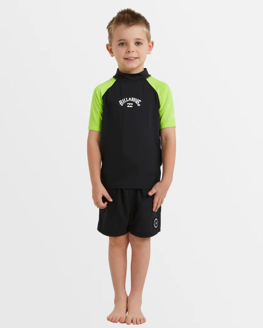 Billabong Groms All Day Arch Short Sleeve Rash Top in black with neon yellow arms on a kids in black shorts
