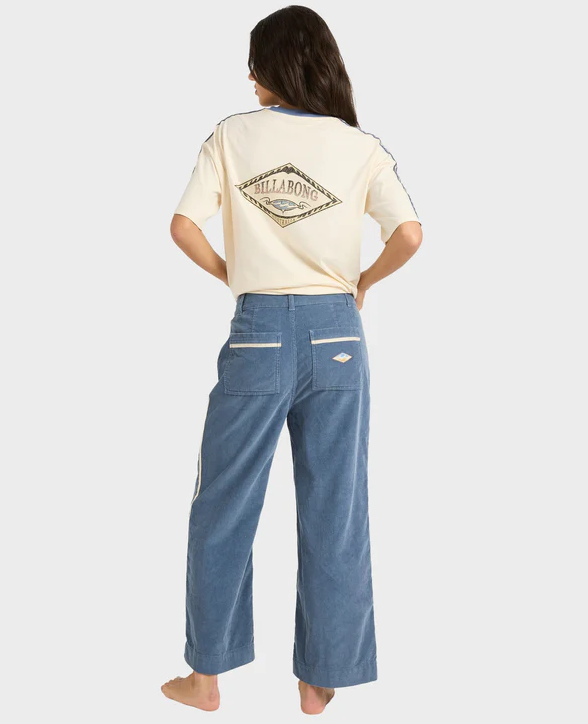 Billabong Sea Tone Women's Corduroy Pants in stone blue on model in off white billabong tee from rear view