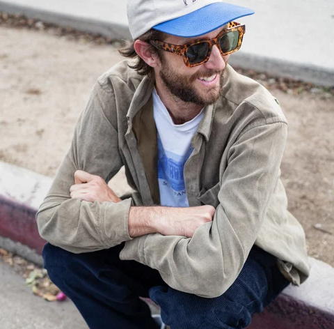 CHPO Brand Max Sunglasses in leopard colourway on model in beige jacket sitting on concrete wall
