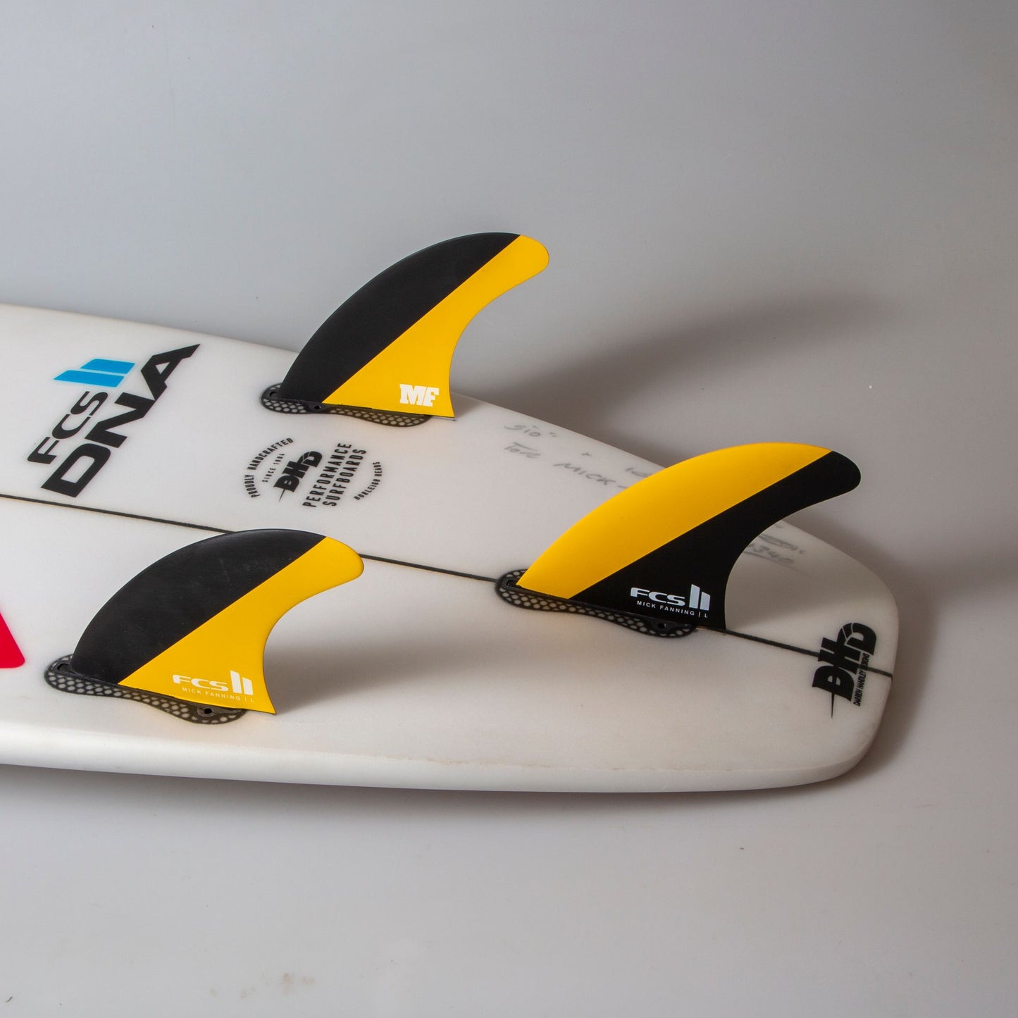 FCS II MF PC Large Tri Surfboard Fin Set in surfboard in black and mango