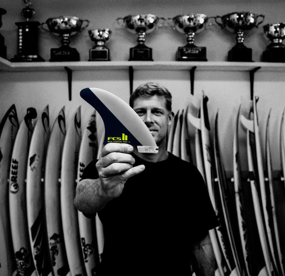 FCS II Mick Fanning Performance Glass Tri Fin Set in black and acid being held by mick fanning