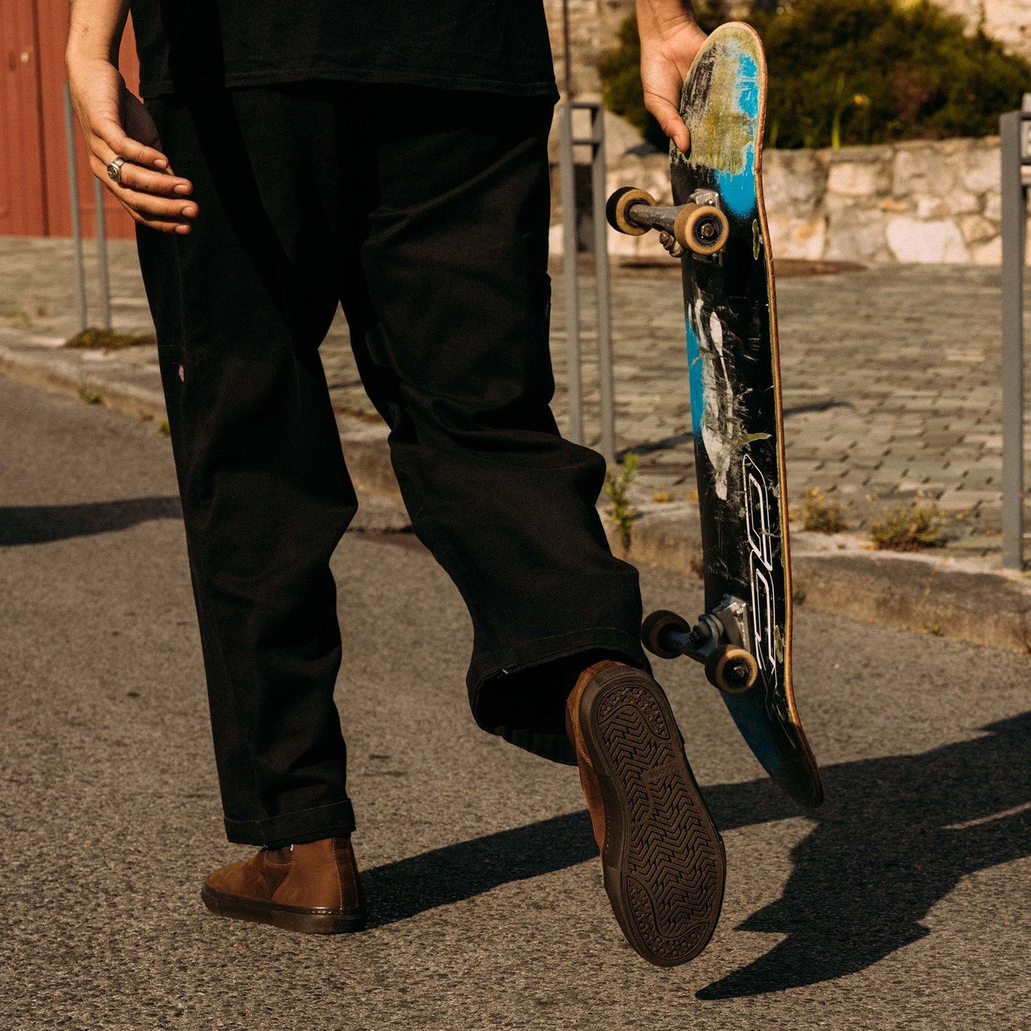 Guy walking with his skateboard wearing Globe Dover II Leather Boots