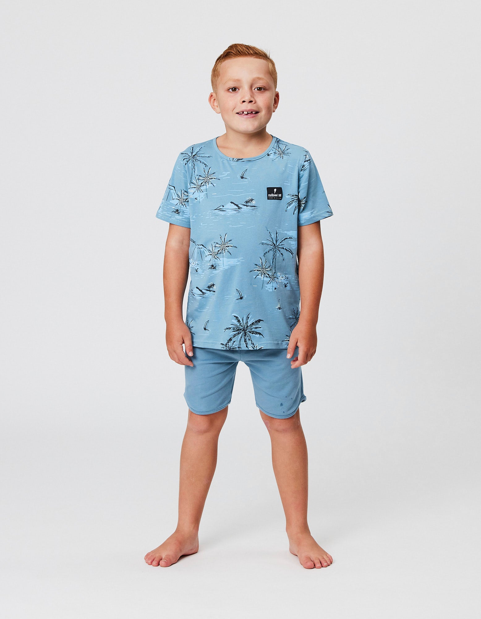Model wearing the Radicool Kids Bermuda Palms Tee in blue