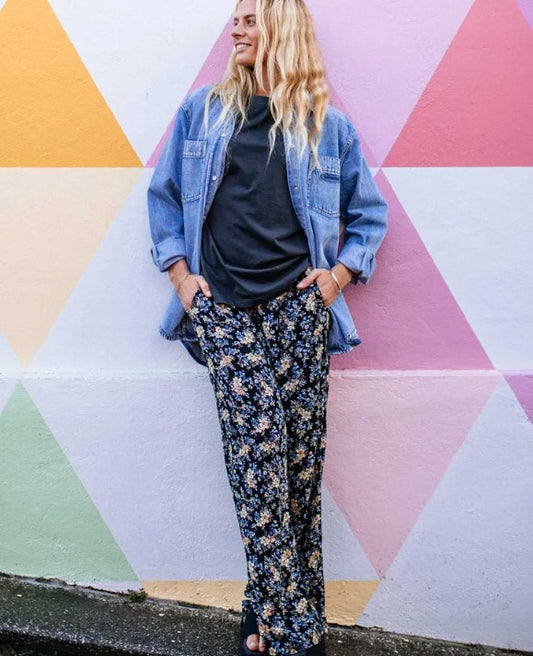 Rip Curl Pacific Rider Ditsy Pants in black based floral on blonde model against multi coloured wall