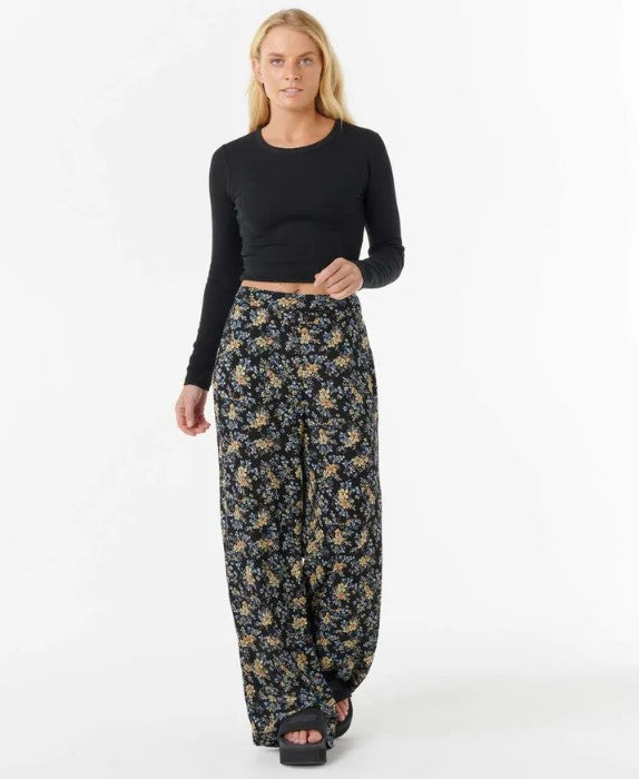 Rip Curl Pacific Rider Ditsy Pants in black based floral material on blonde model in black top