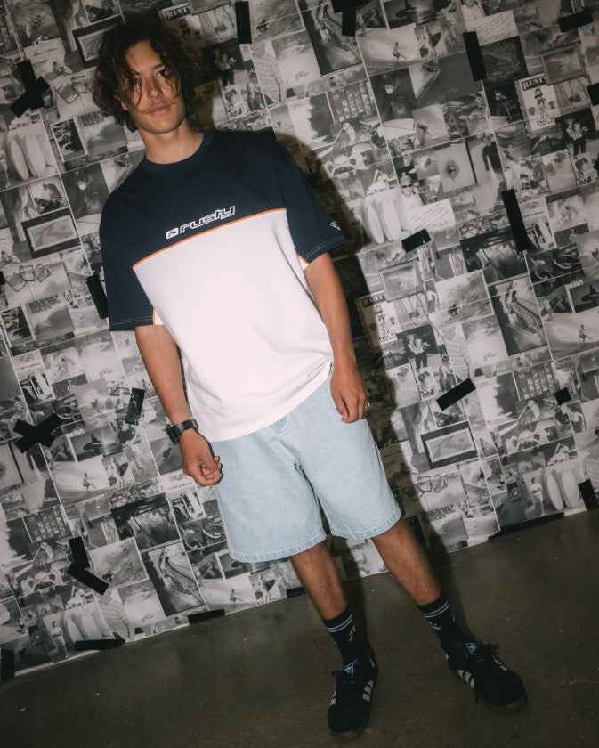 Rusty Flip Daddy 2.0 Denim Shorts in sky blue colourway in lifestyle shot on model with news clipping background