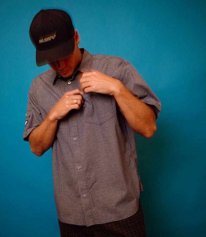 Rusty Flip Daddy Flexfit Cap in carbon colourway on model wearing checked shirt with blue backgorund