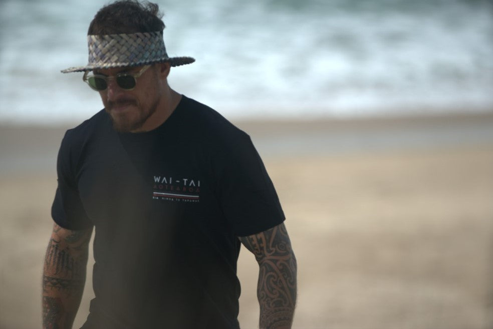 Wai-Tai Mens Tohu Tee in black from front at Okitu Beach on Maia Gibbs
