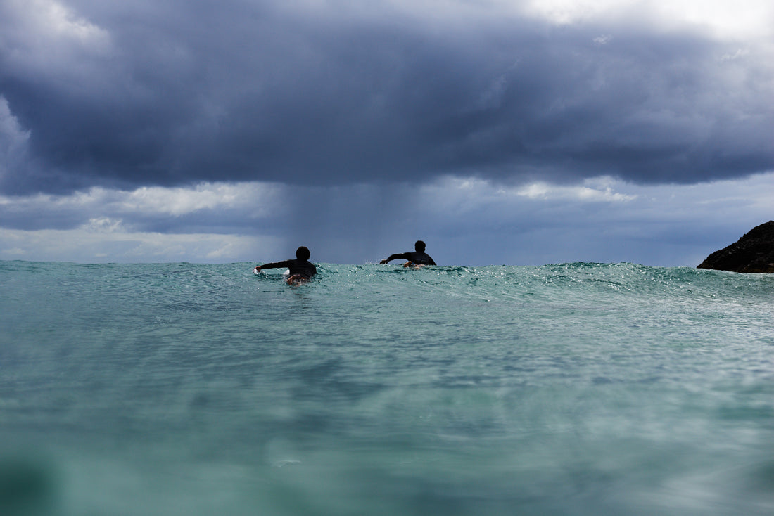 Two Individuals Paddling to Surf in Winter