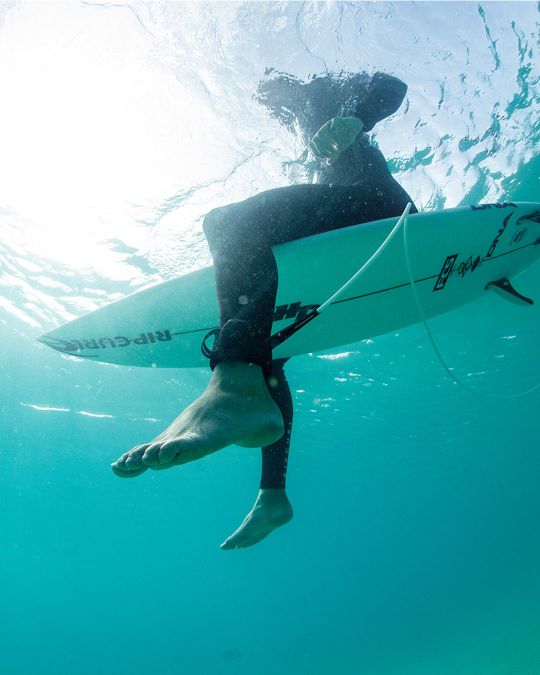 FCS Sharkbanz Pod being worn by a surfer attached to his leash in the water