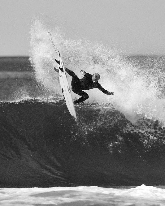 Surfer in O'Neill HyperX wetsuit doing an aerial on his surfboard