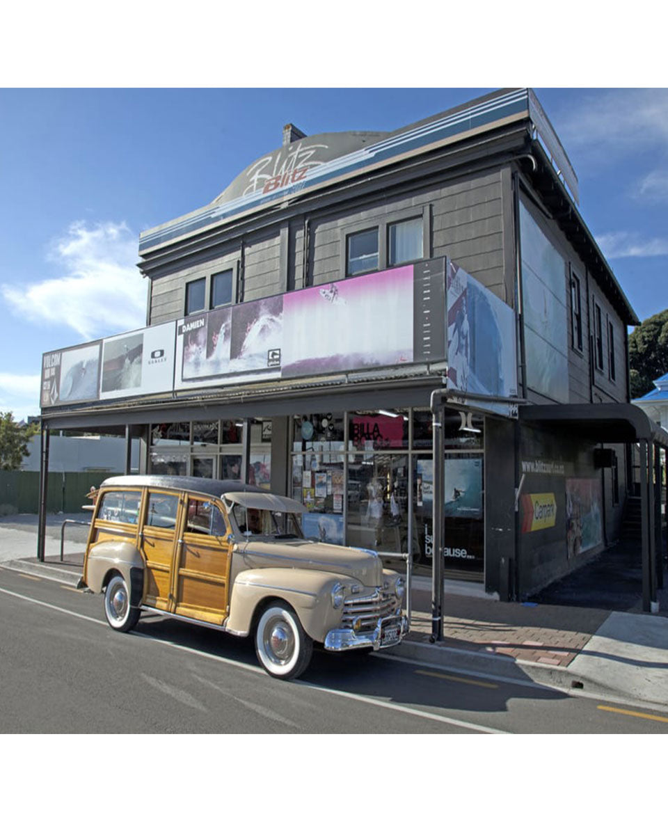Blitz Surf Shop building on Wainui Road with Woody car parked outside on the road