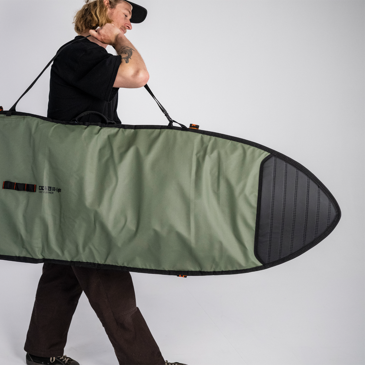 FCS 6'3 Go-Light Day Runner Shortboard Cover in alpine green with black  being carried with shoulder strap