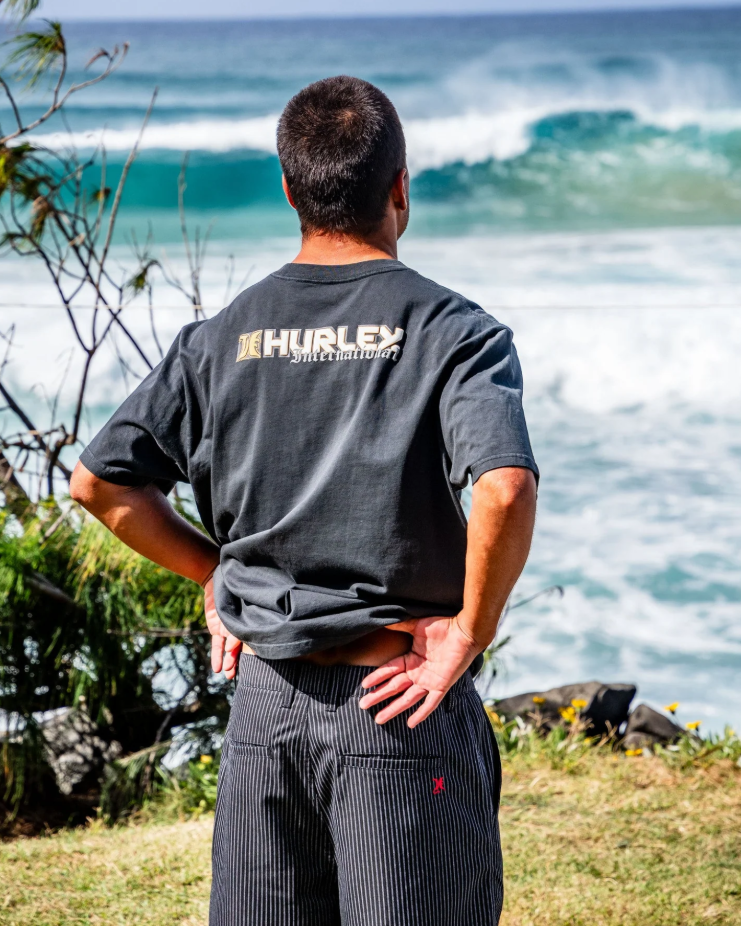 Hurley Rivingston 22" Walkshorts in black stripe on model in Hurley tee at the beach checking the surf