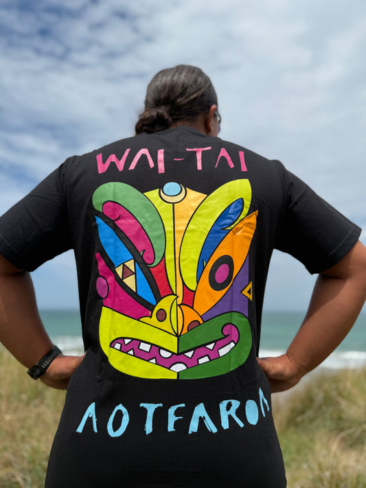 Wai-Tai Aotearoa Ono Whitu Black Unisex Maori Design T-Shirt in black worn by Hine Brooking showing bright tiki design from rear