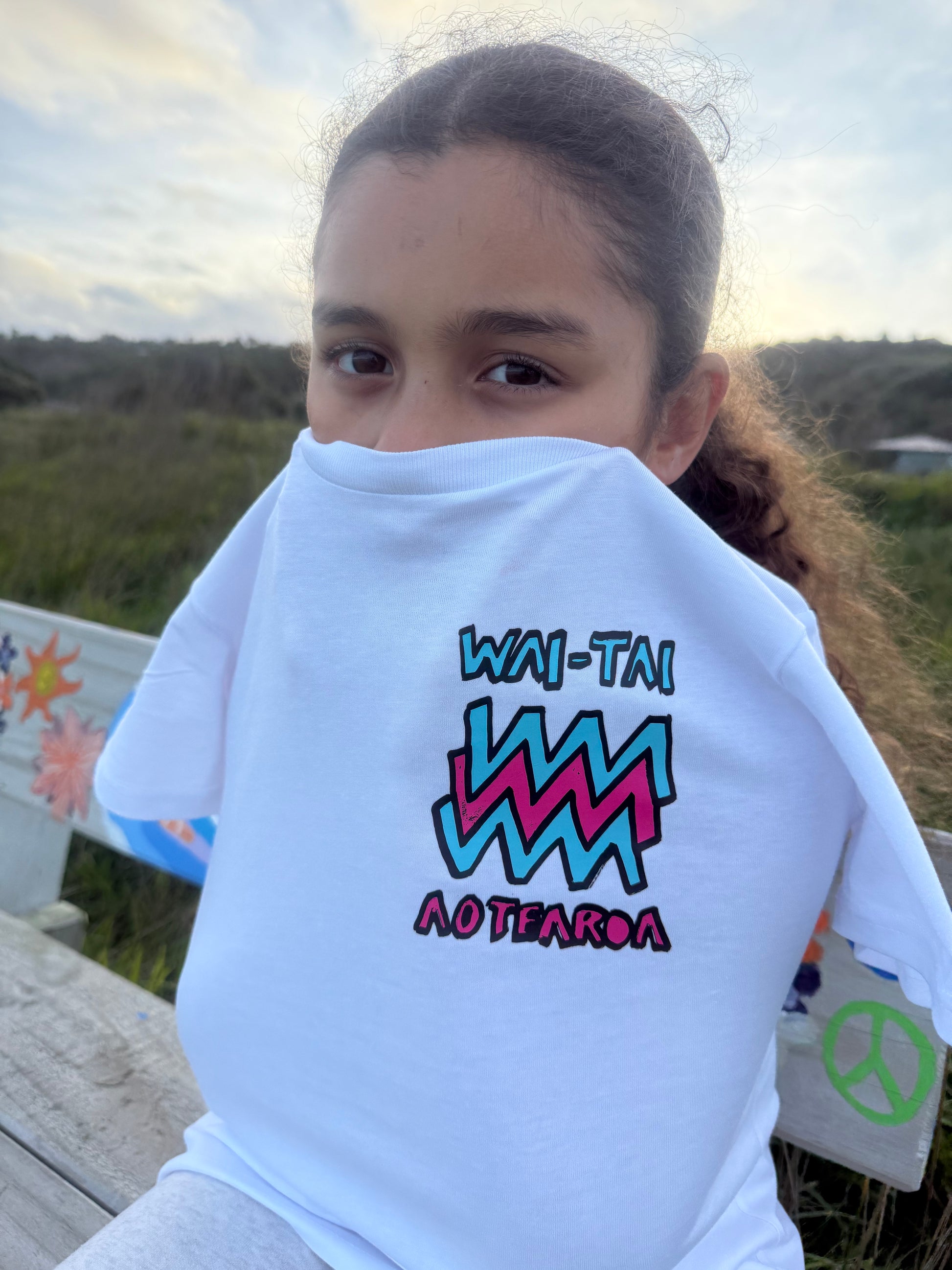 Wai-Tai Kids Mura Maori t-shirt in white from front view at Okltu beach in Gisborne close up
