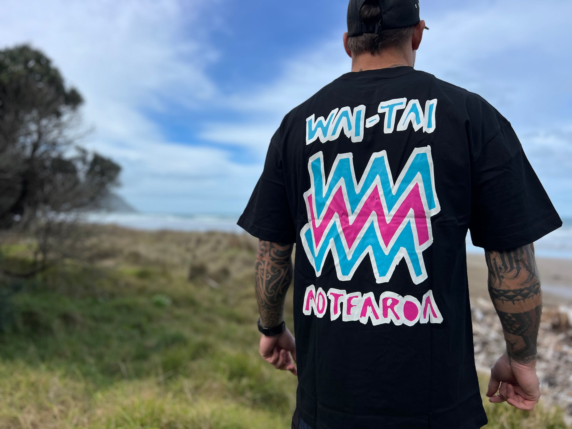 Wai-Tai Aotearoa Mura heavyweight Maori t-shirt in black with flouro print on Maia Gibbs from the back view 