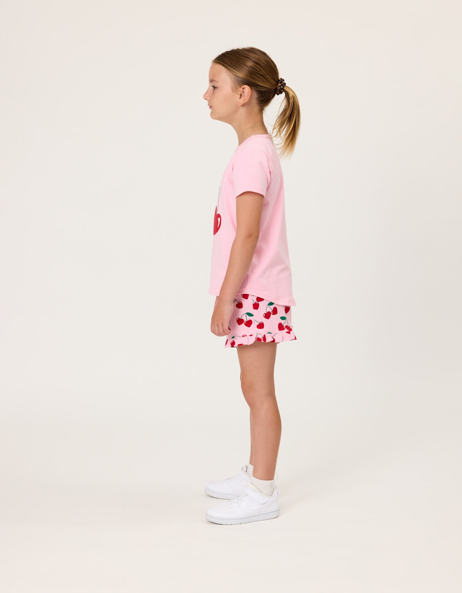 Kissed By Radicool Cherries Girls Frill Shorts in pink on model in pink tee  from side