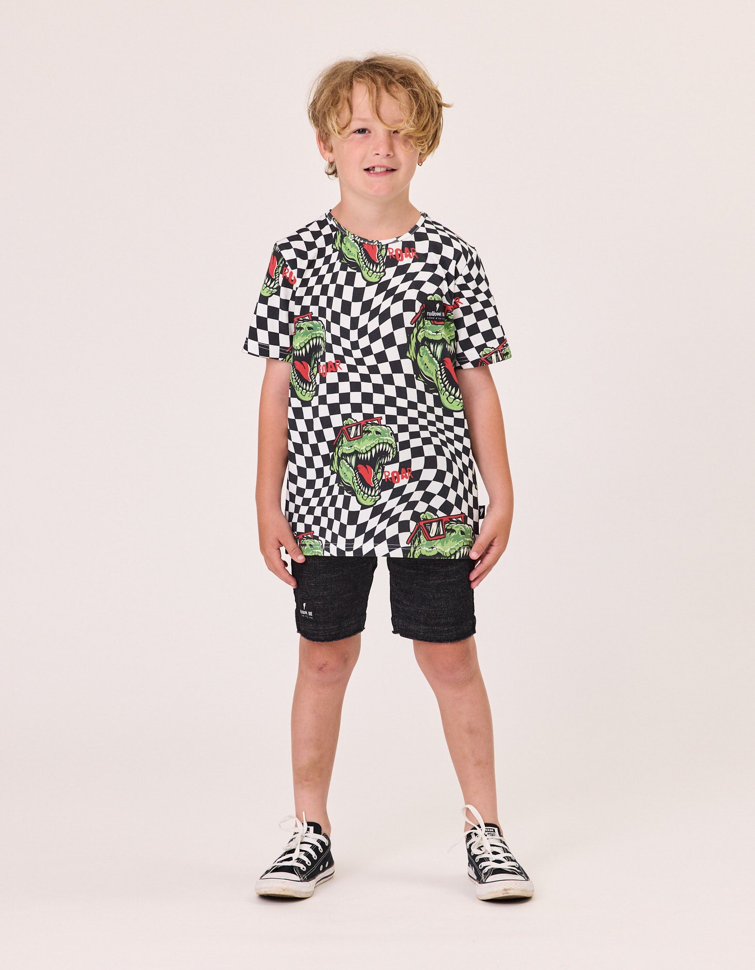 Radicool T-Rex Twisted Chequer Tee
 in black and white checkered with t-rex head imagery on model from the front