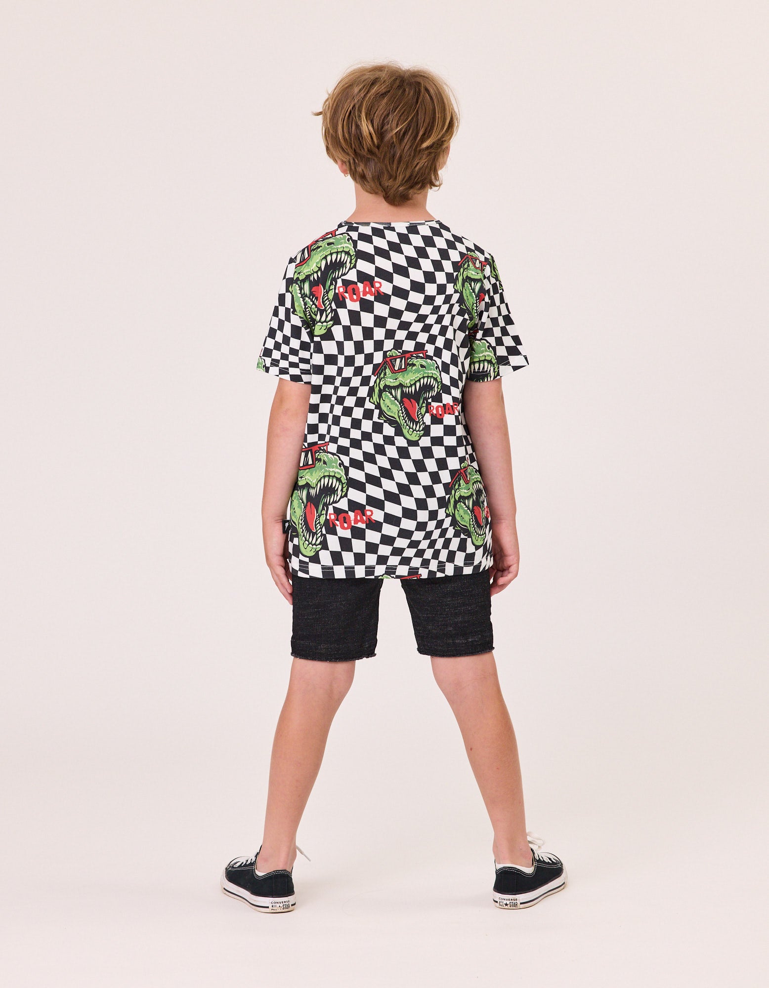 Radicool T-Rex Twisted Chequer Tee
 in black and white checkered with t-rex head imagery on model from the rear