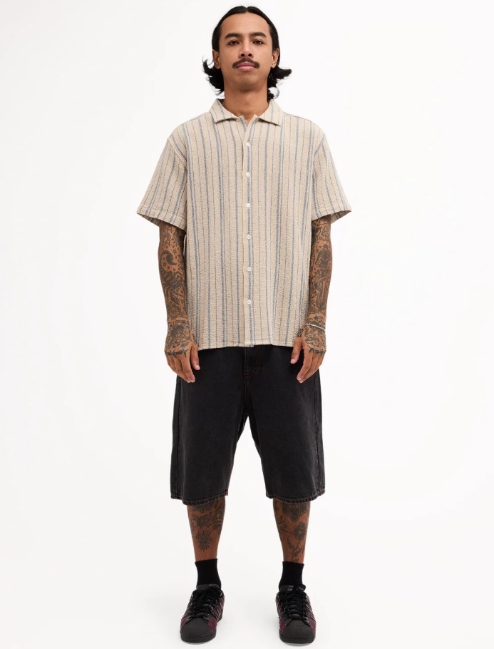 RVCA Vacancy Stripe Short Sleeve Shirt
  in light khaki on model in black denim shorts from front