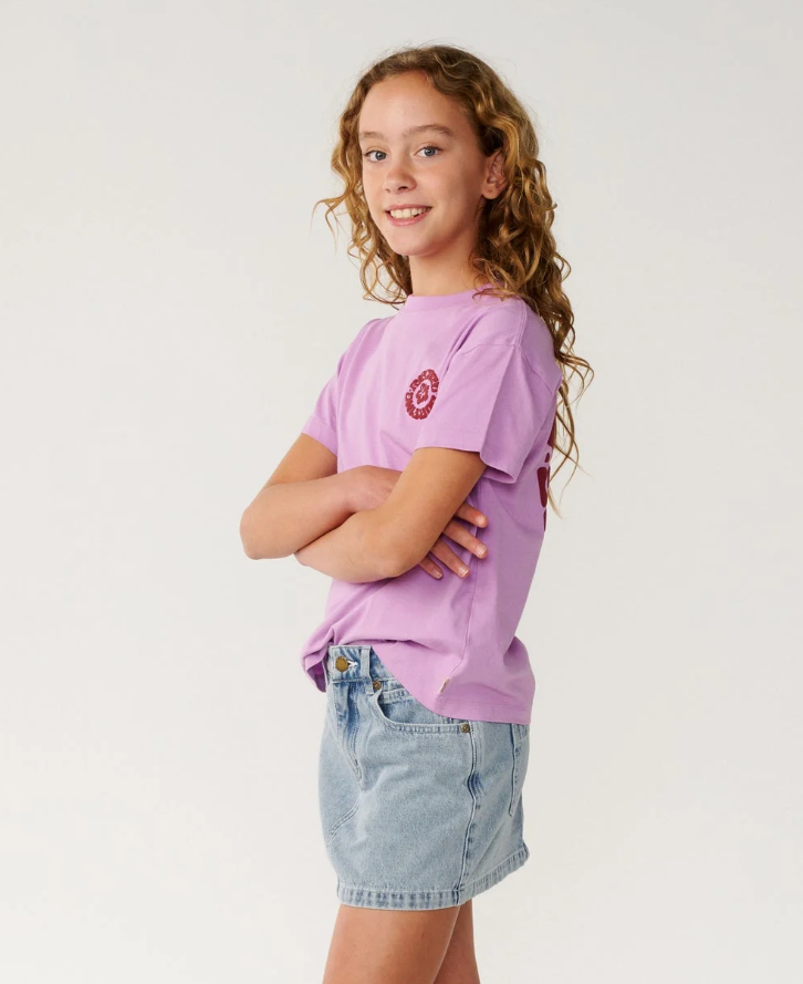 Rip Curl Surf Puff Relaxed Girls Tee
 in bright lilac colourway on young model in denim skirt from the side