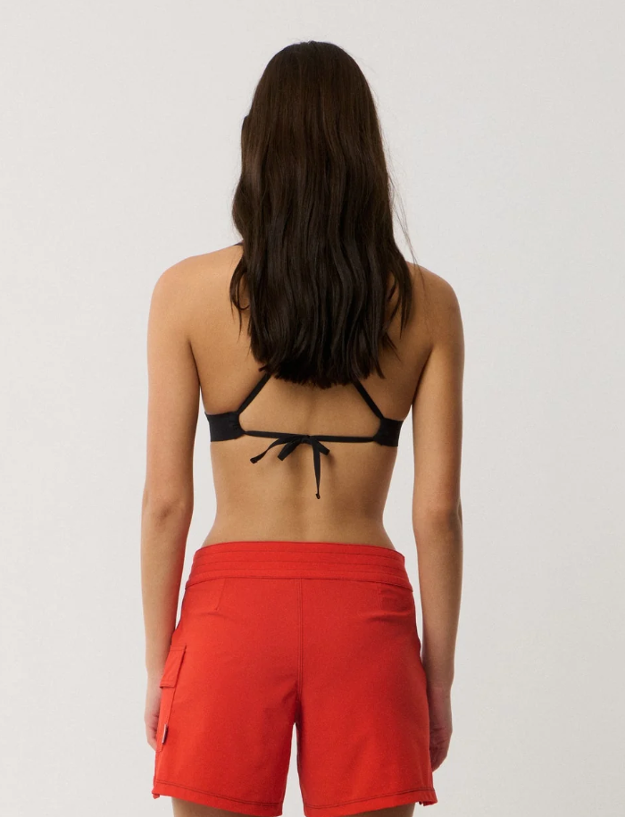 Rip Curl Surf Series Stretch 5" Tech Women's Boardshorts in red on model in black triangle bikini top from the back
