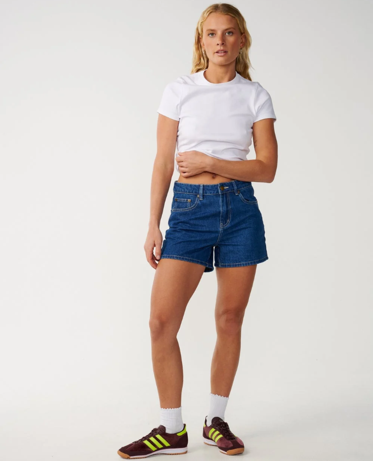 Rip Curl Tabby Women's Denim Shorts in mid blue on model in white tee from the front