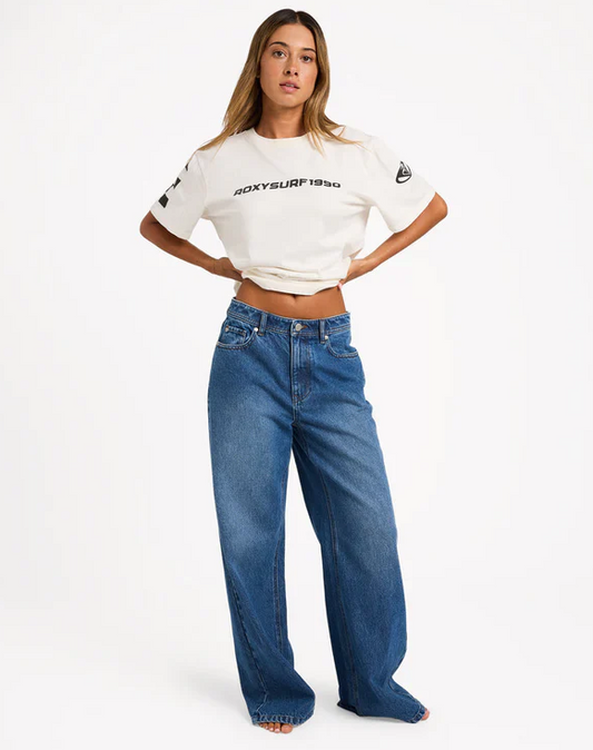 Roxy Backslider Denim Pant in blue on model in white Roxy tee from front