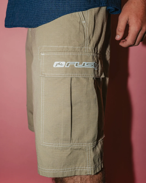 Rusty Comando Rippa 23" Men's Cargo Shorts in putty colourway on model in navy shirt from side