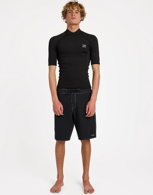 Billabong Absolute Core 1mm Short Sleeve Wetsuit Vest in black form the front on a model in black boardshorts