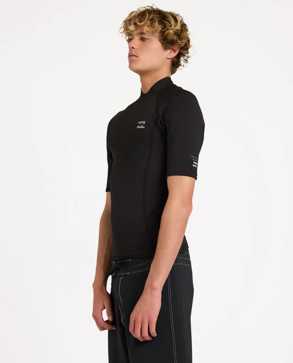 Billabong Absolute Core 1mm Short Sleeve Wetsuit Vest in black form the front on a model in black boardshorts from the side