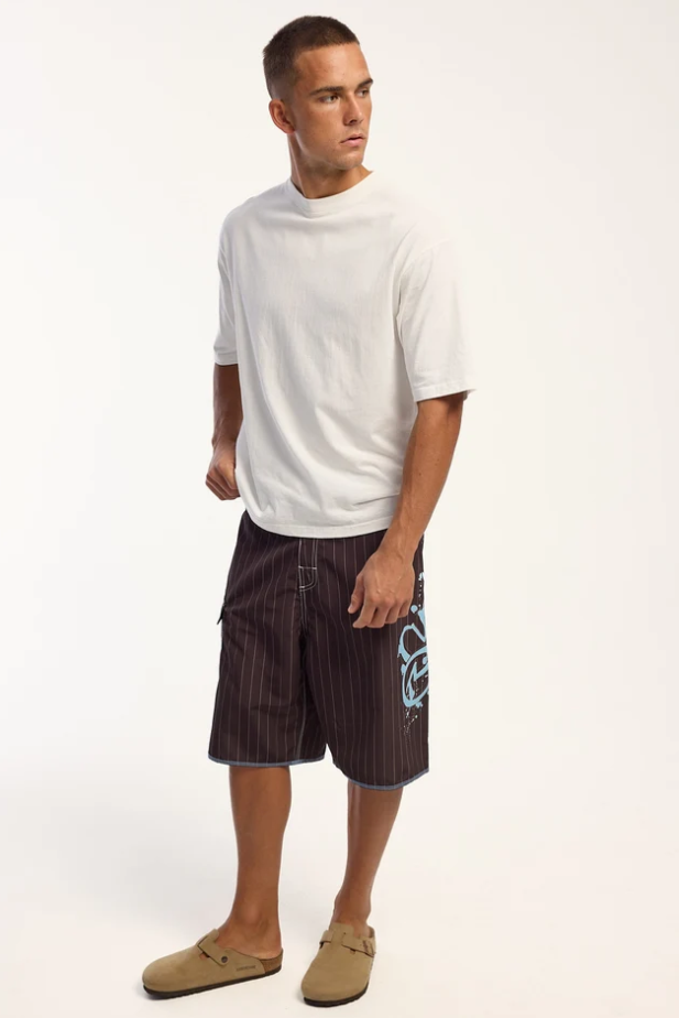 Rusty Scribbla 24" Fixed Waist Boardshorts in java brown with pin stripes on model in white t-shirt from front on an angle