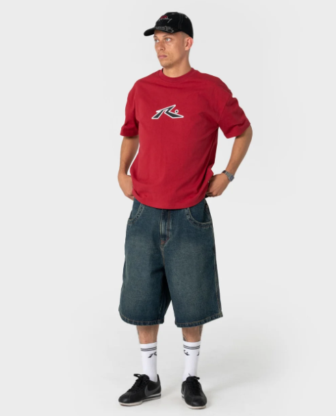 Rusty Shredder 6 Panel Cap in black on model in red Rusty tee and baggy denim shorts