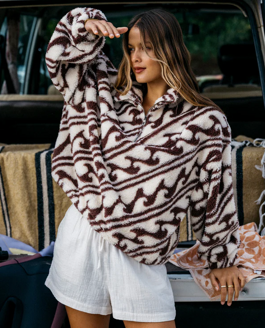 Billabong Dark Wave Half Zip Crew Fleece in teak colourway on model by the back of a car