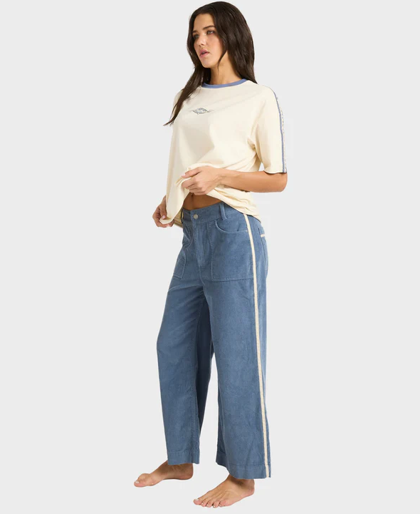 Billabong Sea Tone Women's Corduroy Pants in stone blue on model in off white Billabong tee from side view