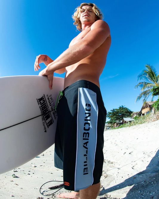 Billabong Spec 73 D Bah Pro 20" Boardshorts in black worn by a surfer holding his Al Merrick surfboard